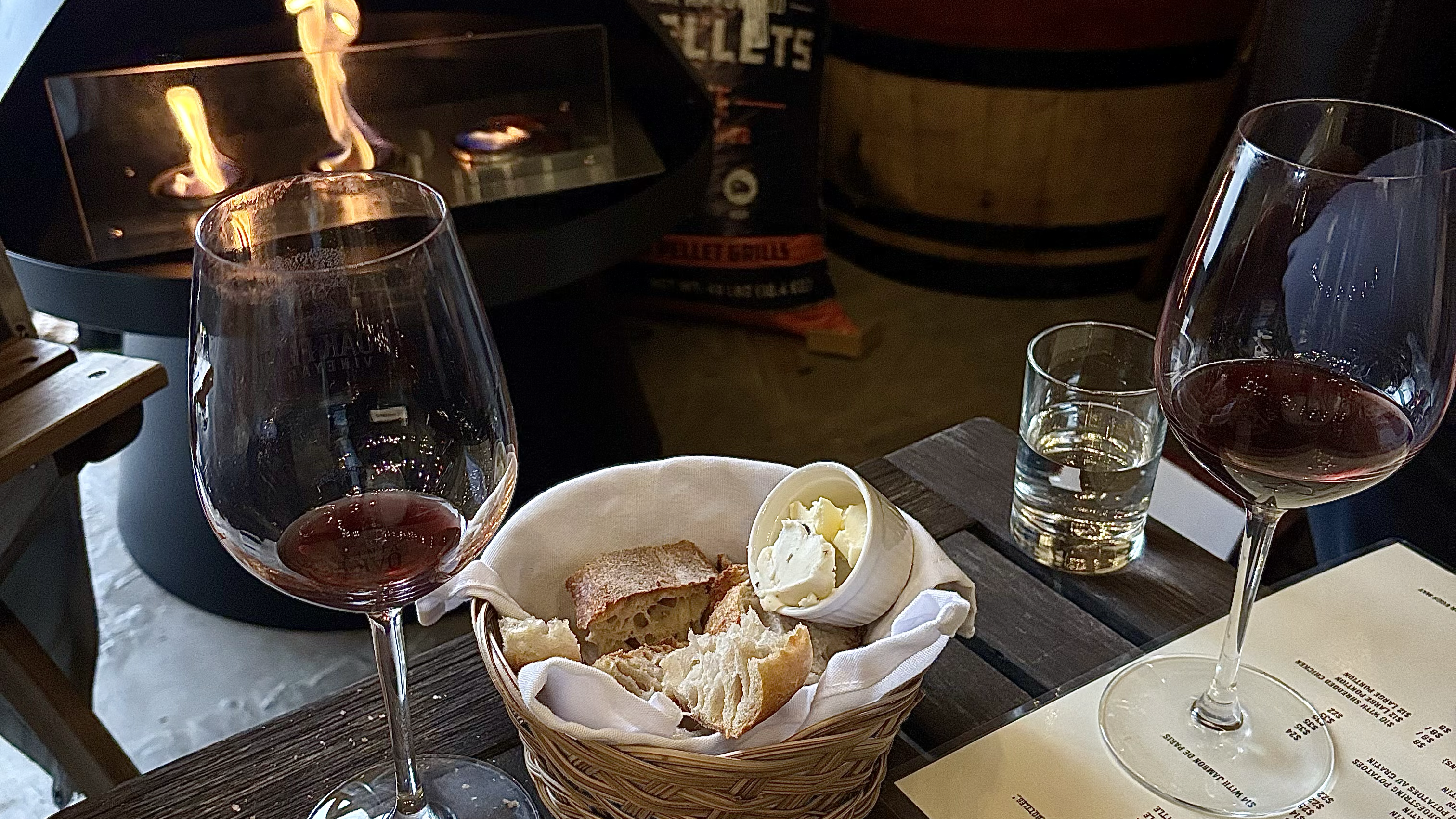 A cozy interior of a wine cellar with a leather couch, a table with a glass of champagne, and a wine rack in the background.